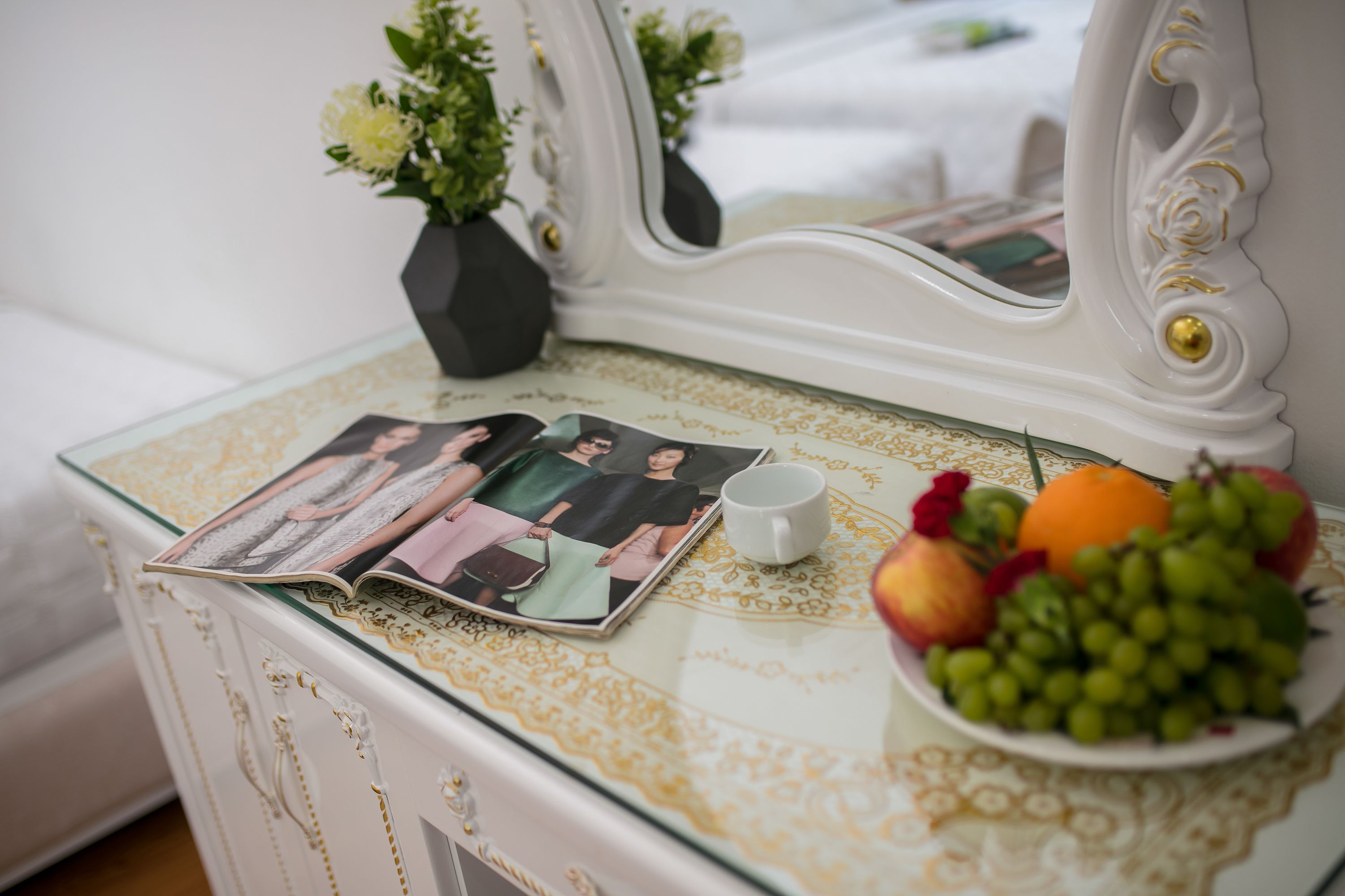 Une table avec un magazine, une tasse et une assiette de fruits.