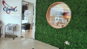 Een modern interieur met een groene wand, een ronde spiegel en borden met 'Country Network Hotel' en 'La Patrie Café'.
