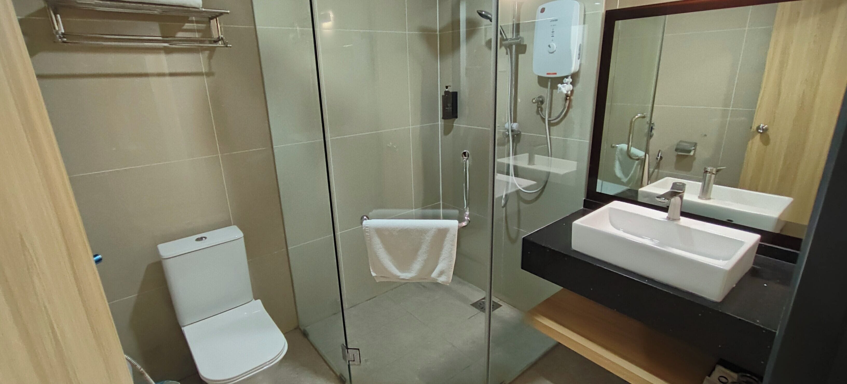 A modern bathroom with a glass-enclosed shower, a white toilet, and a black countertop with a white sink.