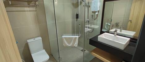 A modern bathroom with a glass-enclosed shower, a white toilet, and a black countertop with a white sink.