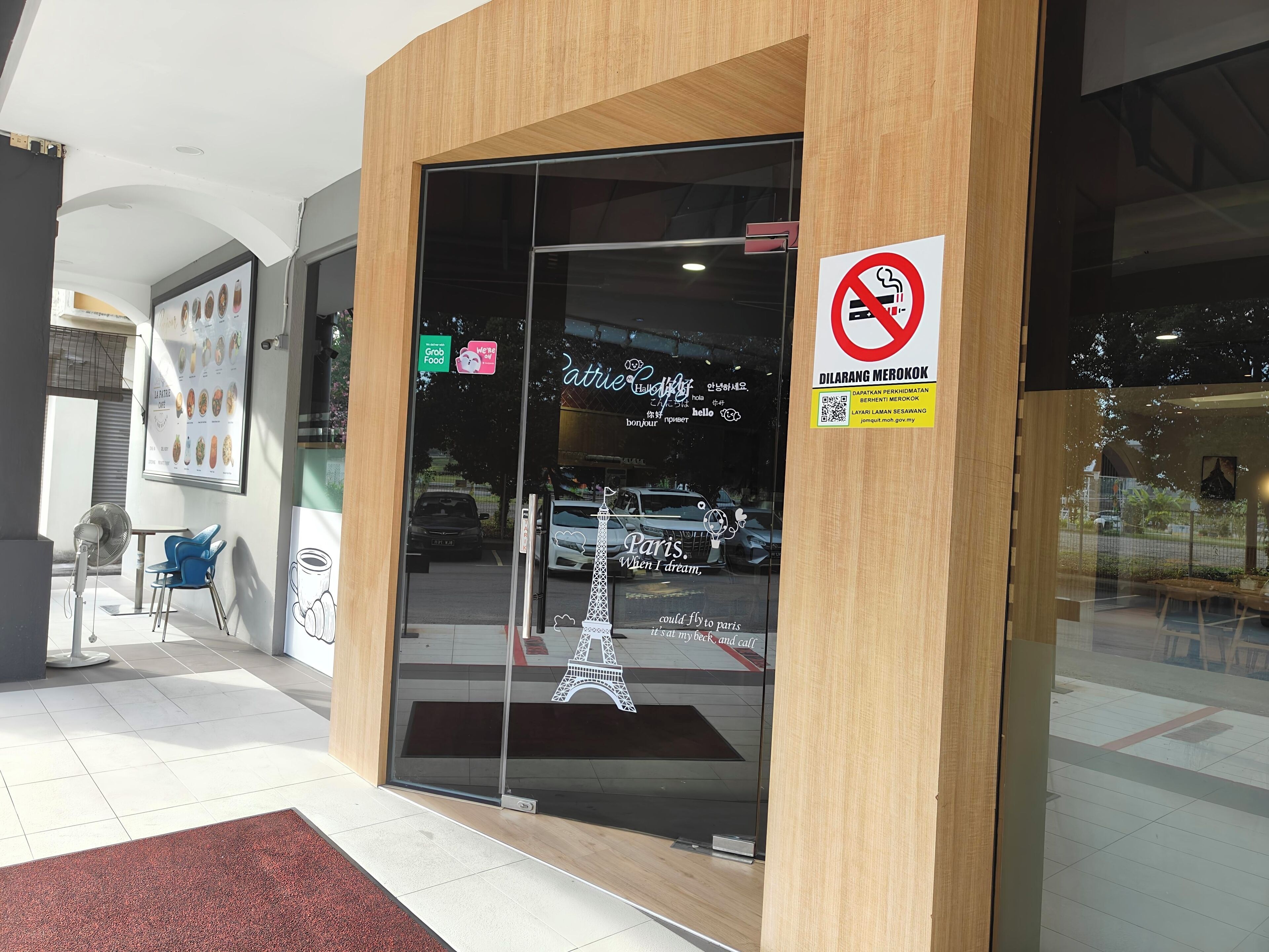 Ein Schaufenster mit einem Rauchverbotsschild, einem Schild mit der Aufschrift 'Grab Food' und einer Paris-Ausstellung.