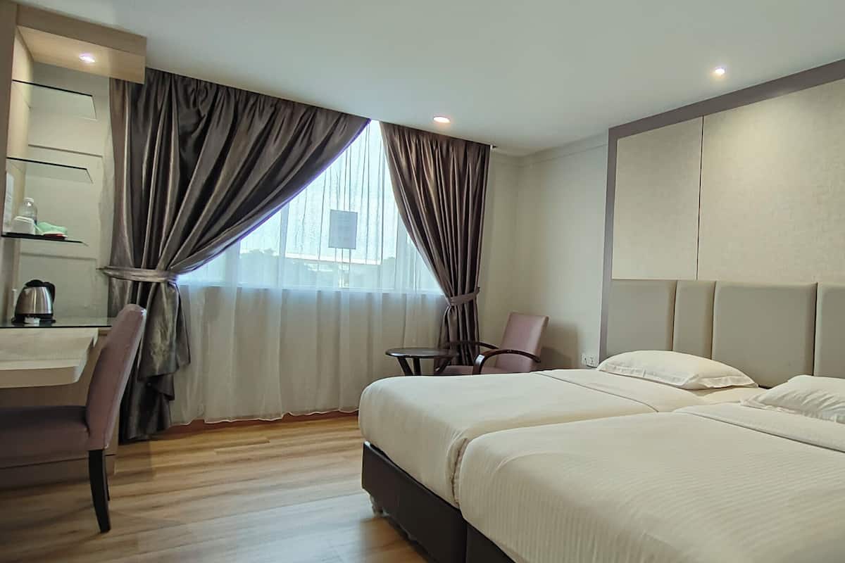 A hotel room with two beds, a desk, a chair, and a large window with curtains.