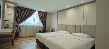 Habitación de hotel con dos camas, un escritorio, una silla y un ventanal con cortinas.