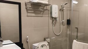 Een moderne badkamer met een douche met glazen wand, toilet, wastafel en handdoekhouder.