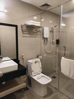 Un baño moderno con ducha acristalada, inodoro, lavamanos y un perchero para toallas.