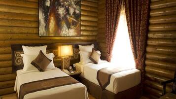 A log cabin room with two beds, a painting on the wall, and a window with curtains.