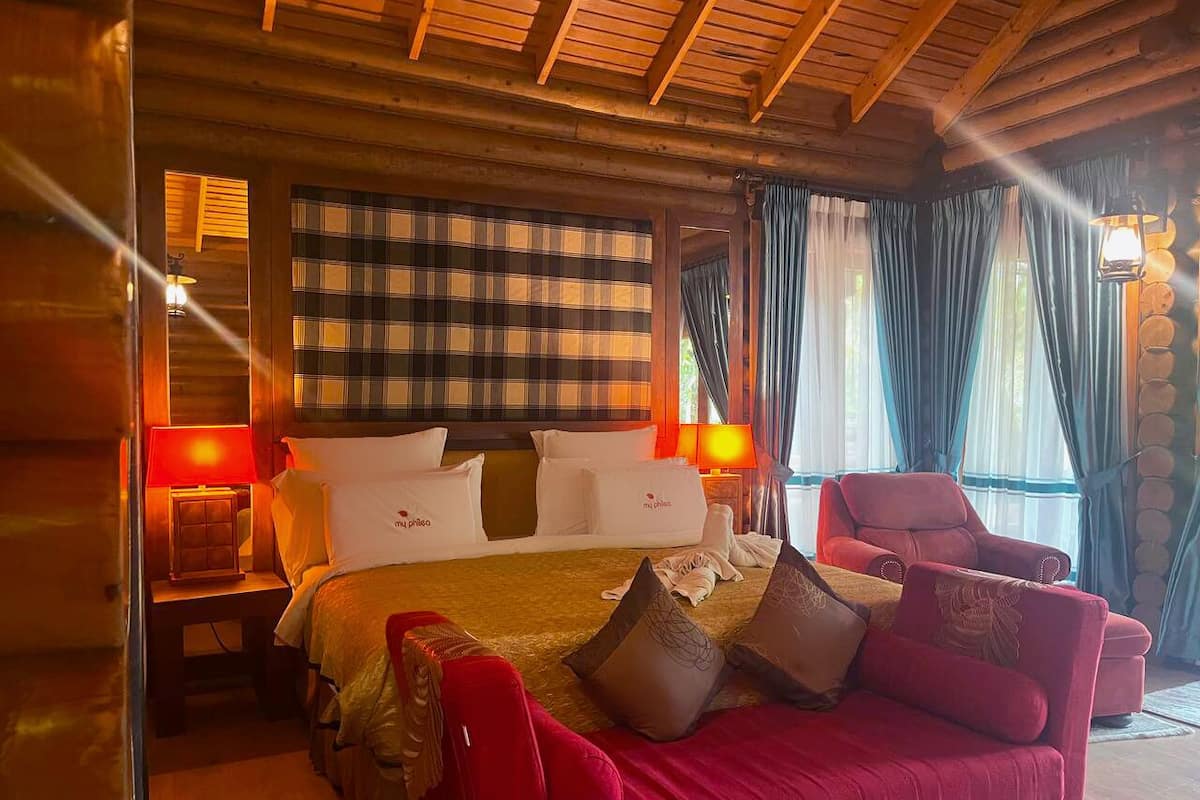 Una habitación acogedora con cama, un sofá rojo y techo de madera.