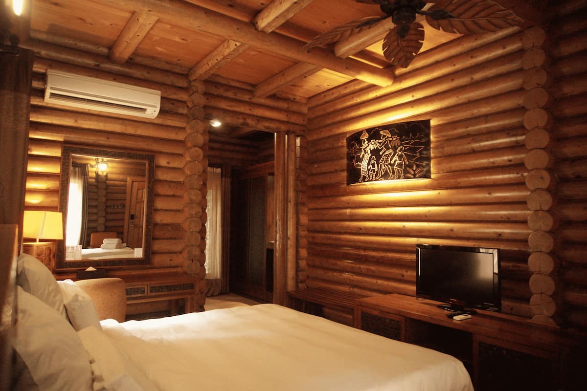 Una habitación tipo cabaña de madera con una cama, un televisor y un espejo.