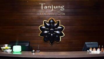 A reception desk with a logo for 'Tanjung Wellness Spa' and a decorative flower design.