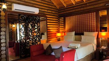 A log cabin-style bedroom with a large bed, red upholstered sofa, and a mirror with decorative ironwork.