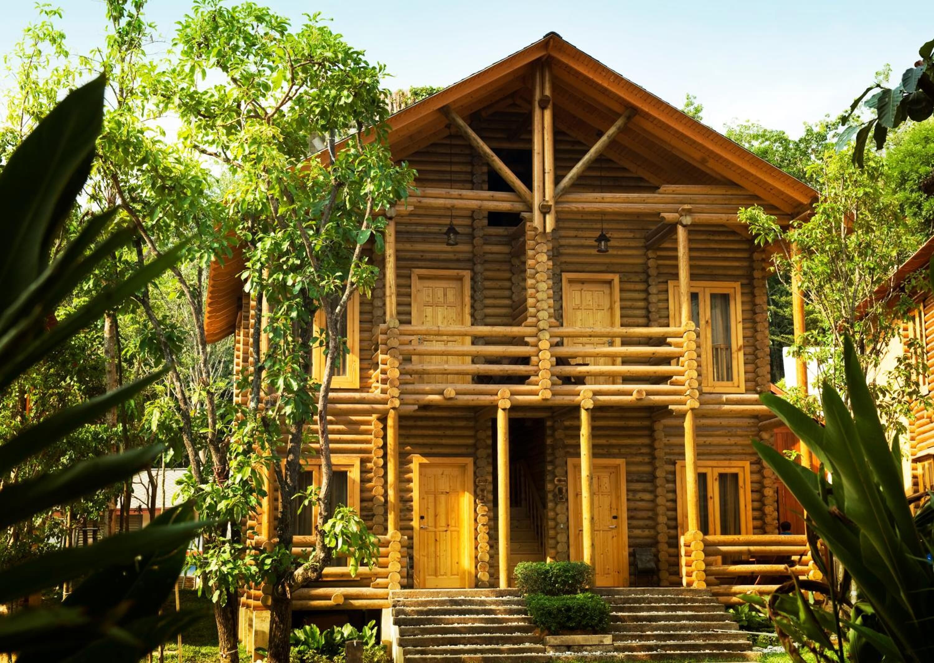 A log cabin with a symmetrical facade, multiple doors, and a central staircase leading to the entrance.