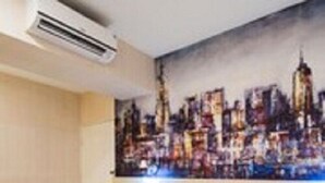 A hotel room with a bed, a painting of a cityscape on the wall, and an air conditioning unit. - Sanduo Hotel (Kaohsiung)