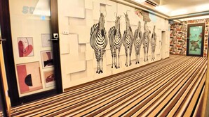 A hallway with zebra wall art, wooden slatted flooring, and a door with a '50%' sign. - Sanduo Hotel (Kaohsiung)