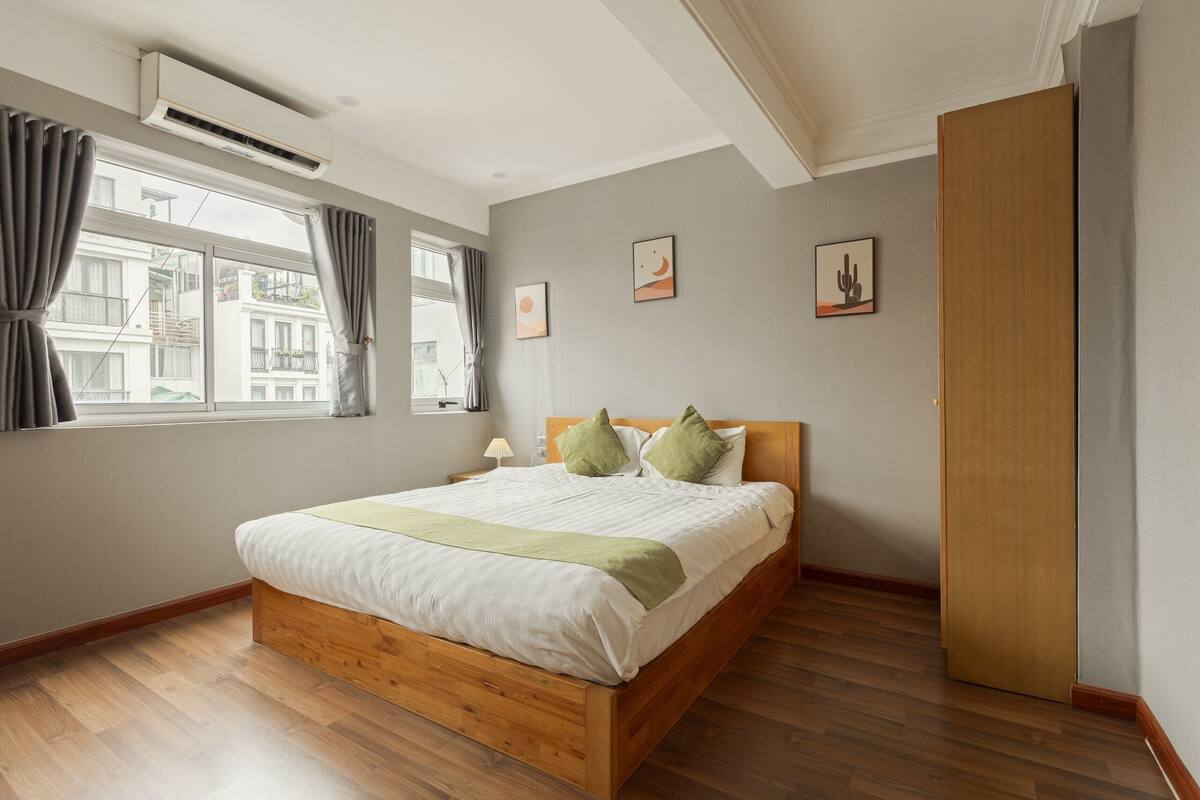 Une chambre avec un lit en bois, une fenêtre avec des rideaux et un climatiseur fixé au mur.