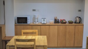 Een keuken met een magnetron, koffiezetapparaat, broodrooster en diverse keukengerei op het aanrecht.