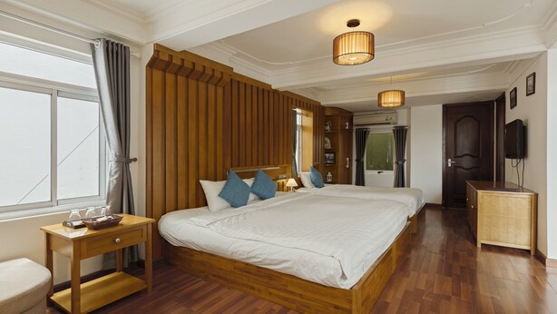 Een ruime slaapkamer met een groot bed, een houten hoofdbord, nachtkastjes en een klein kastje.