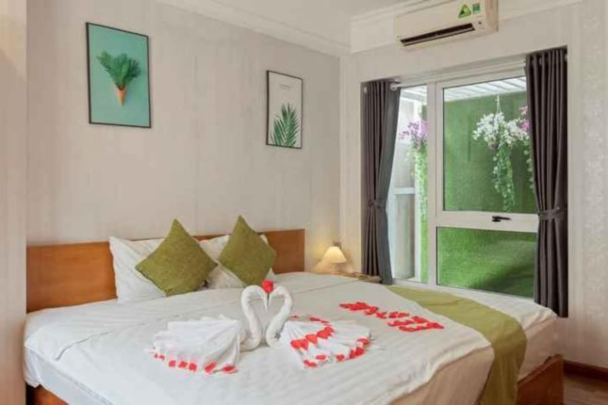 Habitación de hotel con cama, almohadas, ventana con cortinas y aire acondicionado de pared.