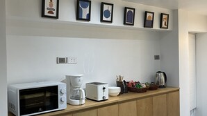 Een keuken met een magnetron, broodrooster, koffiezetapparaat en diverse keukengerei op het aanrecht.