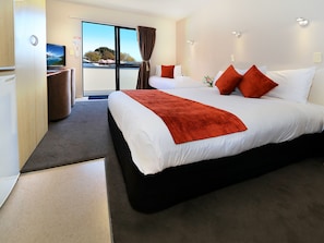 A hotel room with a large bed, a TV, and a view of the outdoors. - Bella Vista Motel Invercargill (Invercargill)