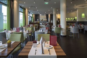 Un restaurante moderno con varias zonas de comedor, cada una con mesas para dos.