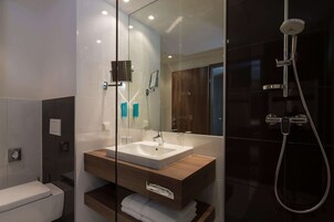 Een moderne badkamer met een douchecabine van glas, een houten wastafelmeubel en een grote spiegel.