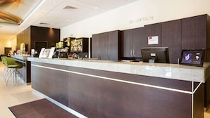 A reception area with a marble counter, dark wooden cabinets, a bar, and a reception desk. - Austria Trend Hotel Doppio (Vienna)