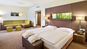 A hotel room with two beds, a sofa, a coffee table, and a lamp. - Austria Trend Hotel Doppio (Vienna)