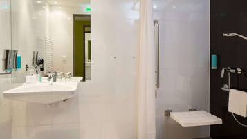Un baño moderno con lavabo blanco, espejo y zona de ducha.