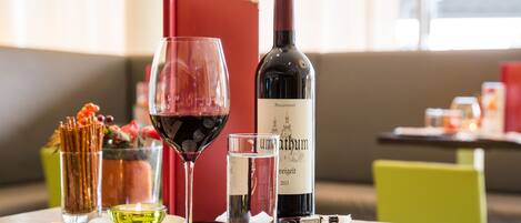 A table with a bottle of wine, a glass of red wine, a glass of water, and a menu.
