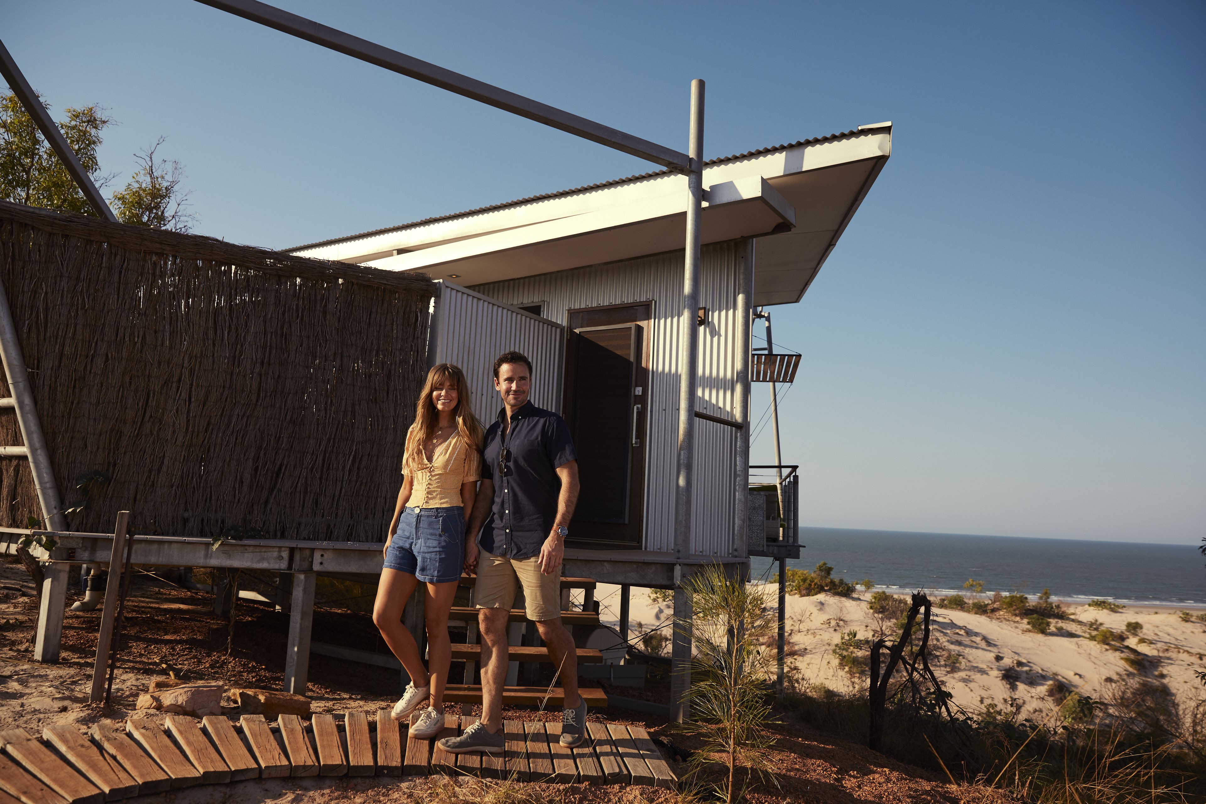 Una casa moderna frente a la playa, con terraza de madera y vista al océano.