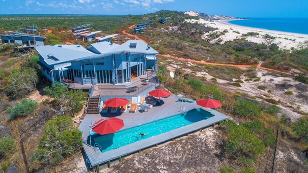 A modern resort with a pool, outdoor seating, and a view of the beach and ocean. - The Berkeley River Lodge (Oombulgurri)
