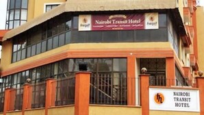 Un immeuble à plusieurs étages doté d’une façade en verre incurvée remarquable et d’une enseigne indiquant « Nairobi Transit Hotel ».
