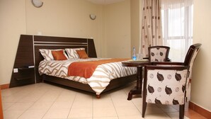 Une chambre à coucher avec un lit, une table de chevet, une chaise et une fenêtre avec des rideaux.