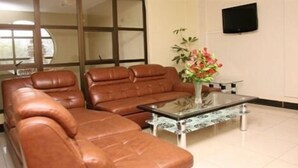 Un coin salon avec un canapé et une table basse en verre, une plante en pot et un téléviseur à écran plat fixé au mur.