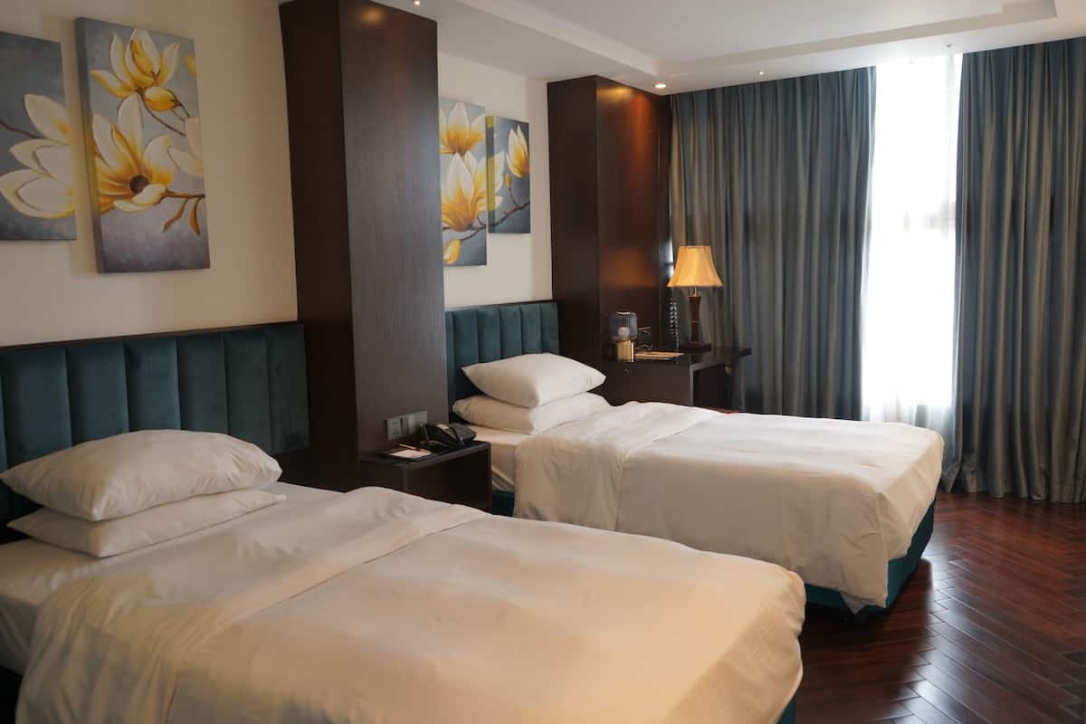 Une chambre d’hôtel avec deux lits, une table de chevet, une lampe et des œuvres d’art accrochées au mur.