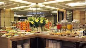 A buffet with various food items and a centerpiece of yellow flowers. - Golden Silk Boutique Hotel (Hanoi)