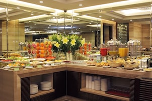 A buffet with various food items and a centerpiece of yellow flowers.