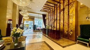 A lobby with a reception desk, a green armchair, and a chandelier. - Golden Silk Boutique Hotel (Hanoi)