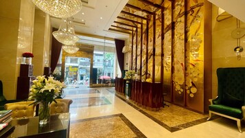 A lobby with a reception desk, a green armchair, and a chandelier.