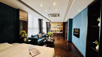 A hotel room with a bed, a sofa, a coffee table, and a TV.