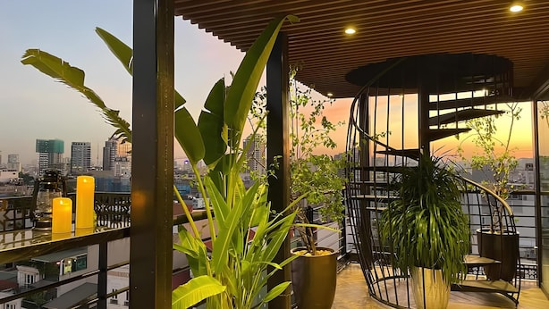A rooftop terrace with potted plants, a spiral staircase, and a city skyline view. - Golden Silk Boutique Hotel (Hanoi)