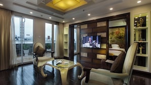 A modern living room with a glass coffee table, leather armchairs, a television, and a bookshelf. - Golden Silk Boutique Hotel (Hanoi)