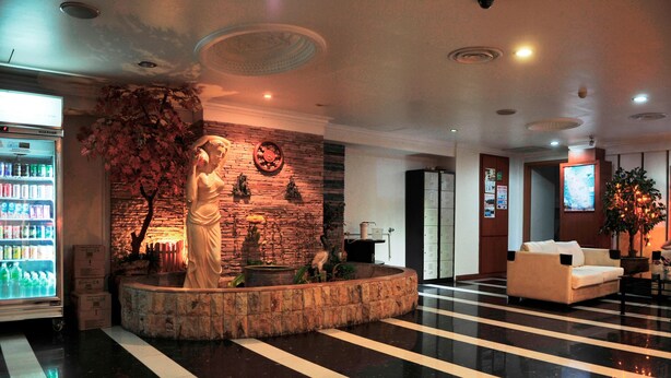 Un hall d’entrée avec une fontaine en pierre, une statue, un réfrigérateur et un canapé.