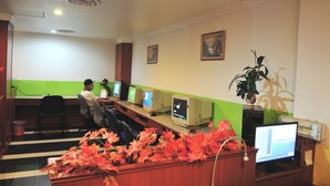 Une salle informatique équipée de plusieurs ordinateurs de bureau, d’une grande plante en pot et d’un mur d’accent de couleur verte.