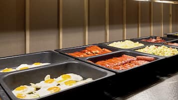 Un bufé con diversas opciones de comida, incluyendo huevos, salchichas y otros platos.