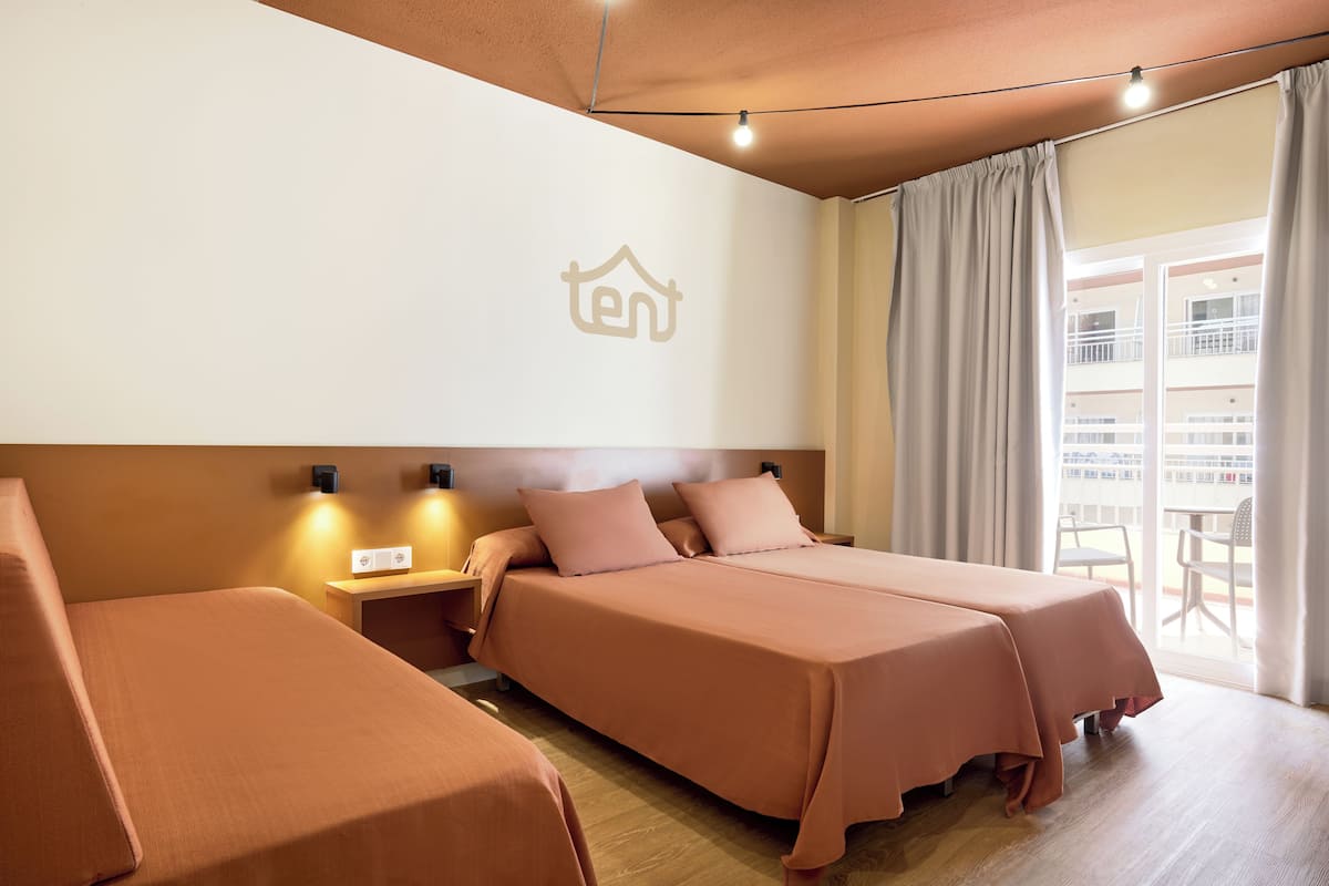 Une chambre d’hôtel avec deux lits, une table de chevet et un luminaire fixé au mur.