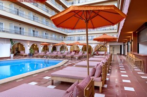 Una piscina al aire libre, sombrillas, sillones reclinables de piscina