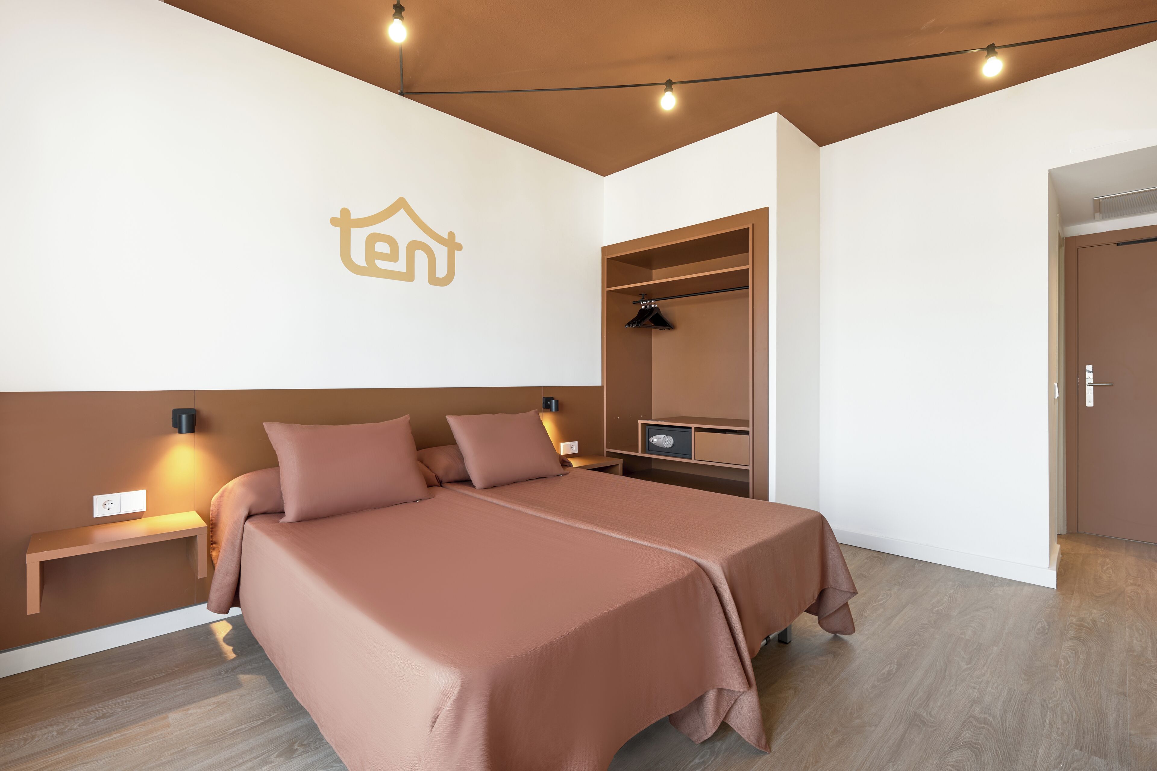 A modern bedroom with a bed, bedside tables, a wardrobe, and a wall-mounted light fixture.