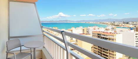 Un balcón con vistas al mar, una silla y una mesa.