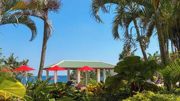A tropical resort with palm trees, a gazebo, and a view of the ocean.